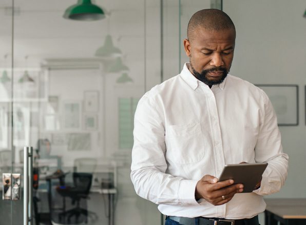 man in a button-down white work shirt holding a tablet